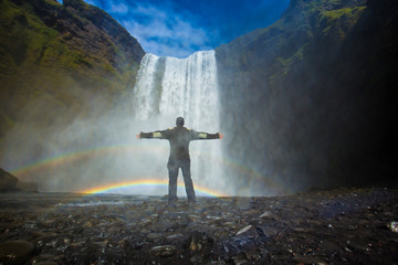 A young man under the Skogafoss waterfall. Iceland