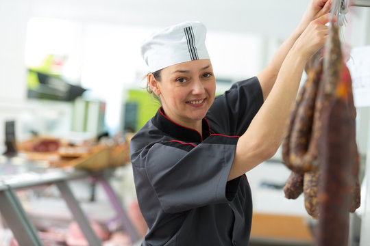 female butcher processing sausages at meat factory