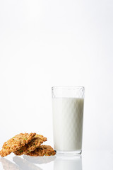 A glass filled with milk on a white background. White drink. Cow's milk. Homemade cookies on a white background. Pyramid of cookies. Cookies on top of each other.