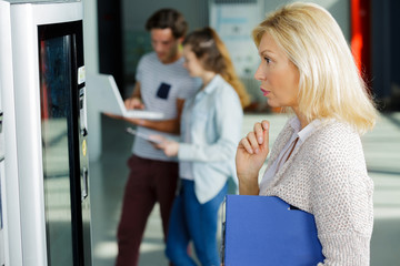 mature woman reading choices at vending machine
