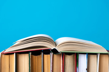 Simple composition of hardback books, raw books on wooden deck table and blue background. Stacking books without inscriptions, empty spine. Back to school. Open book. Place for text