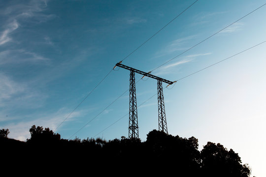electricity transmission pylon silhouetted against blue sky.