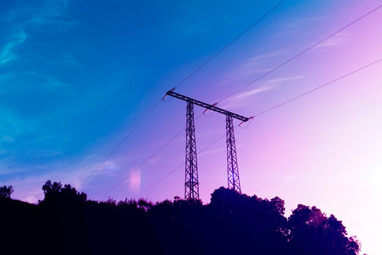 electricity transmission pylon silhouetted against blue sky.
