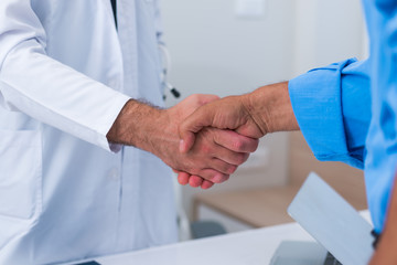 Handshake between a doctor and his senior ( old ) patient.