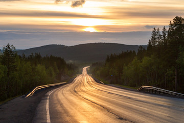 Asphalt road to mountain on sunset. Picturesque landscape scene.