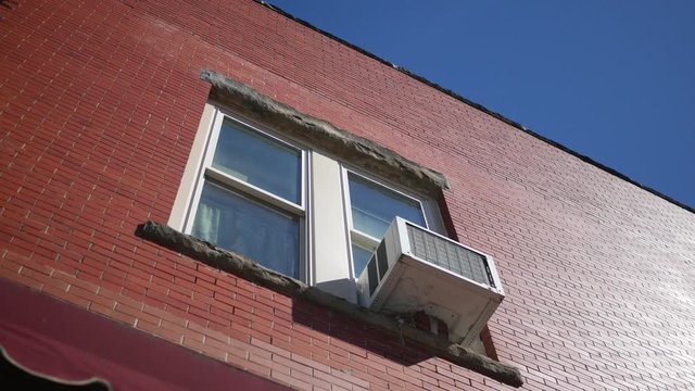 Establishing shot of second story apartment with air conditioner unit sticking out of window