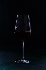 Bottle and glass of red wine on black background