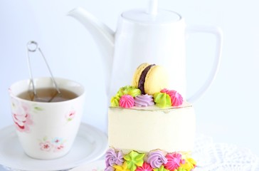 A piece of cake with cream cheese and a Cup of tea on a white background.