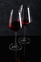 Bottle and glass of red wine on black background
