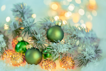 Christmas and New Year Holiday greeting card. Beautiful green ball, pine branches and a garland in the snow. Shallow depth of field. Toned image. Copy space. Blurred bokeh background.