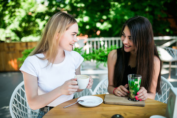 Obraz na płótnie Canvas Two young happy friends having drinks in cafe