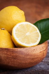Juicy ripe citrus on old wooden background. Fresh lemons  in a bowl