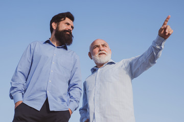 Happy grandfather and father over blue sky and clouds background. Men generation. Retirement parent. Aged father. Family tradition.