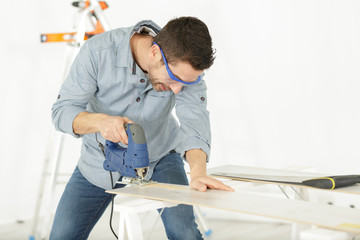 man is cutting wood indoors