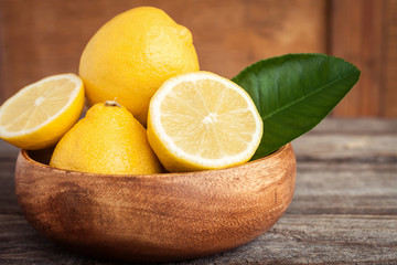 Juicy ripe citrus on old wooden background. Fresh lemons  in a bowl