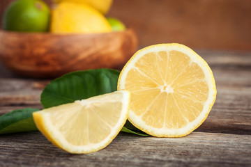 Juicy ripe citrus on old wooden background. Fresh lemons and limes in a bowl