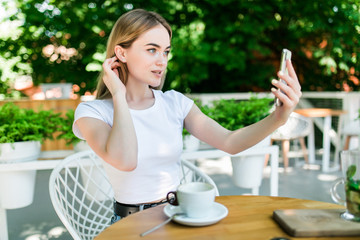 Young woman talking video call on the phone in a restaurant or cafe. Afternoon coffee breaks and...
