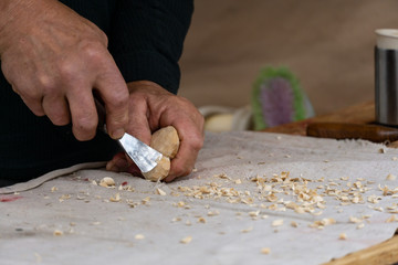 Man hands woodcrafting a heart; small wood shavings around