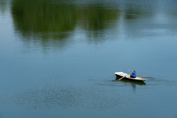 Fototapeta premium Fisherman rowing a boat on pond