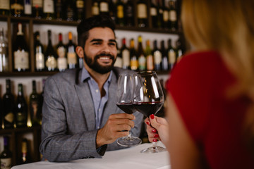 Attractive young couple clinking by wine glasses in restaurant during date.