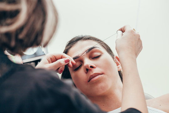 Attractive woman in beauty salon on facial hair removal threading procedure