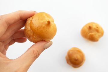 Woman take profiterole, close-up. Cream puff cakes dessert on white background. French pastry