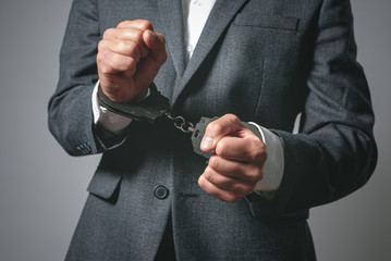 Handcuffs on a businessman hands close up.