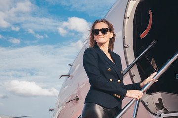 beautiful businesswoman is seating near the business jet airplane at a sunny day