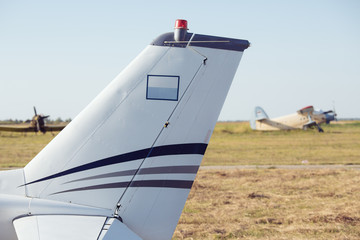 Airplane tail fin - sky with white clouds and old plane in background