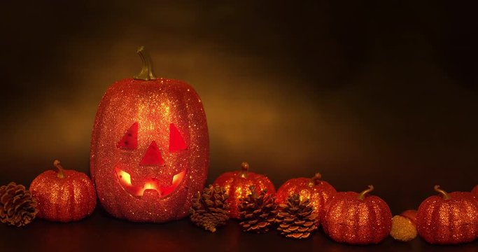 Halloween pumpkin face with a flickering light inside surrounded by ornaments with steam around