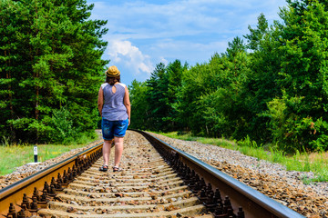 Lonely young woman on a railway in forest
