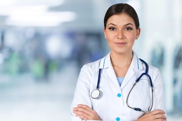 Attractive young female doctor with blurred hospital interior on background