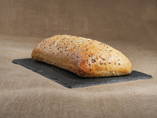 Fresh sourdough bread with nuts on a slate plate and hessian cloth. Selective focus.
