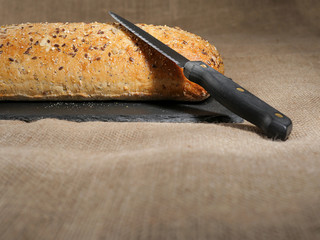 Sourdough bread with nuts and black knife, Rustic hessian tablecloth, Still life, Copy space.