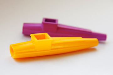 a yellow and purple kazoo on white background, a musical instrument for children