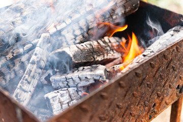 Fire in brazier. Сhargrill with burning wood. Prepare charcoal before grilling meat.
