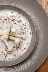 Enoki cream soup in a ceramic bowl, close up. Exquisite dish. Creative restaurant meal. Fine dining concept.