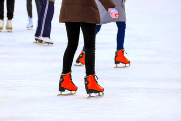 Winter rink. The girl in the red skates riding on the ice. Active family sport during the children s holidays and the cold season. School sports clubs