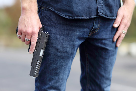 Closeup of a man holding a pistol safely with the finger off of the trigger.