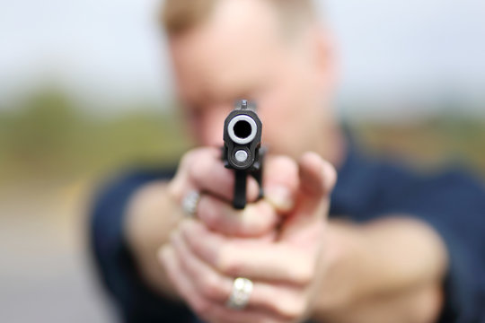 Closeup of a man aiming a pistol.