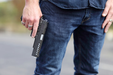 Closeup of a man holding a pistol safely with the finger off of the trigger.