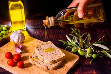 A Mediterranean cook prepares a slice of bread with virgin olive oil, tomatoes and garlic, a traditional breakfast in the Mediterranean countries.