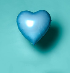 Single light blue big metallic heart balloon object for birthday on light blue mint 