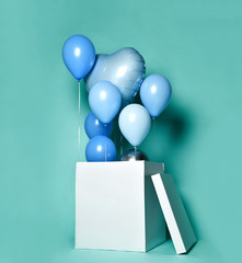 Huge Gift or present box with blue pastel color balloons and latex metallic heart on light green blue pastel color background 