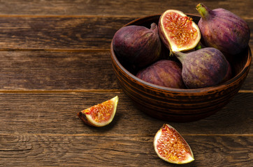 figs in a rustic ceramic bowl on the dark wooden background