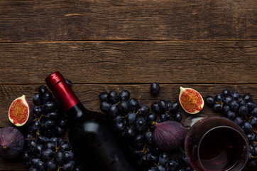 Red wine in a bottle, cheese, grapes, figs on a wooden board, background