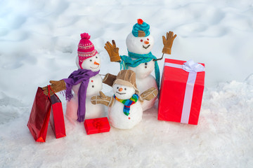 Christmas snowman with shopping bag and Christmas gift. Greeting snowman family, parenthood concept. Snowman with shopping bag and gift on the white snow background.