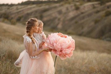 Mom with daughter in pink fairy-tale dresses walk in nature. The childhood of the little princess....