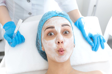 Close-up face of young girl relaxes and gets pleasure from facial massage. Moisturizing, cleaning...