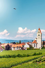 Panoramic view of lake of Lake Constance. Zeppelin, apple trees and Catholic Church St. Johann Baptist in Hagnau on the picture. © Lena Wurm